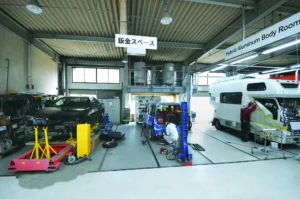 認証工場内の鈑金スペースで作業中のキャンピングカーや、分解中の車両